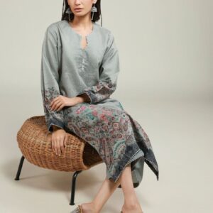 A woman wearing a grey printed kurta with floral patterns near the hem and sleeves, paired with matching straight trousers and transparent heels.