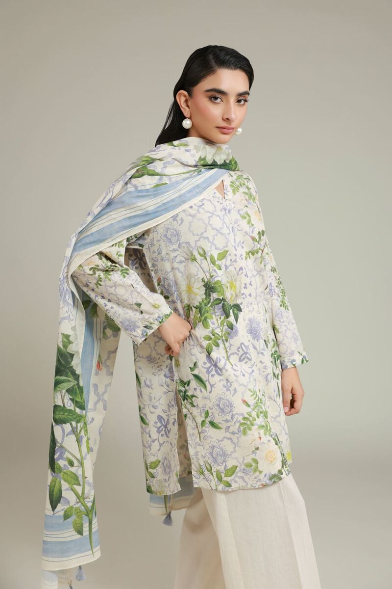 A model wearing a A22-26-103FC1 3-piece lawn suit by Khaadi. The outfit features a long kurta with intricate vertical patterns and detailed borders, paired with dyed trousers and a matching printed dupatta with striped and floral designs. The model stands against a plain background, holding the dupatta, with product fabric details displayed on the left side.
